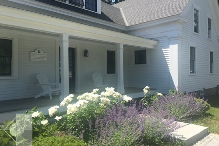 Landscaping at an office in Damariscotta, ME featuring a granite slap and seasonal flowers.