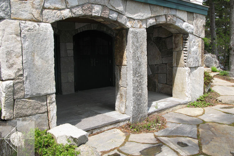 Landscape design with the lower level of this home is veneered in stone.