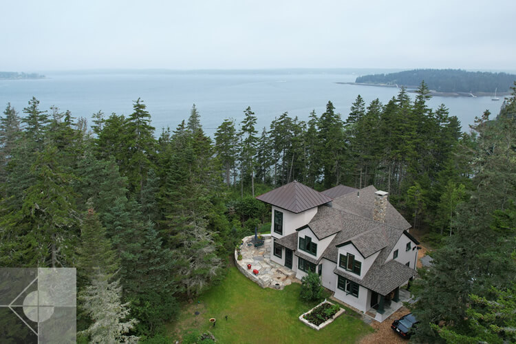 Drone photo of the side of this house with the ocean in the background.