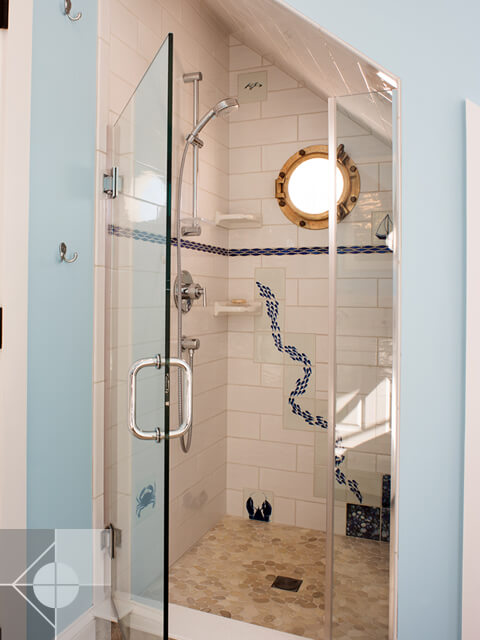 Custom tiled walk in shower with round window.